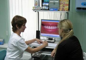 гигиенист стоматологической клиники Диал-Дент объясняет пациенту как правильно пользоваться зубными протезами