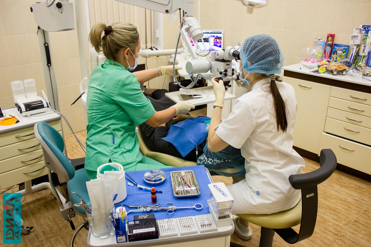 стоматолог-эндодонтист лечит зубы под микроскопом