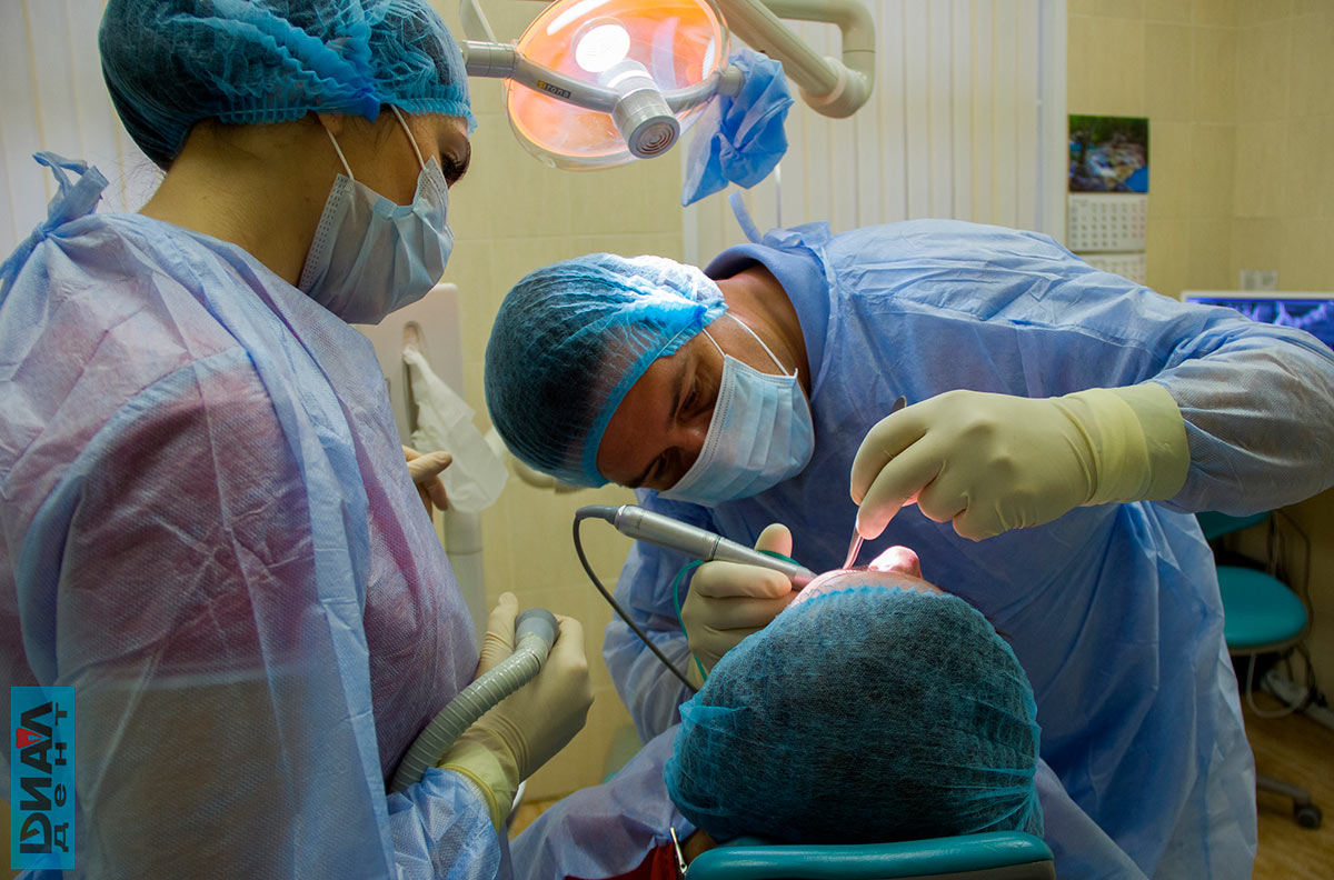 хирург устанавливает имплант зуба