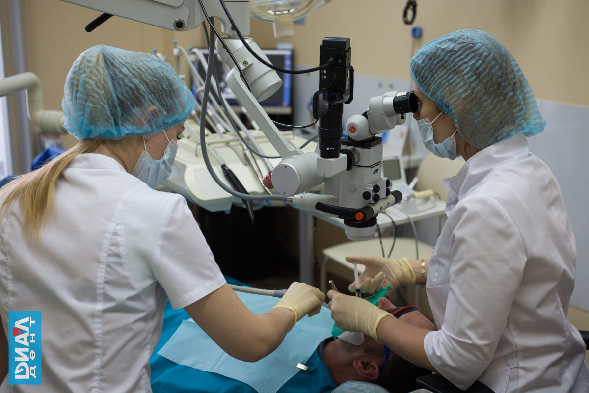 стоматолог с микроскопом лечит зубы